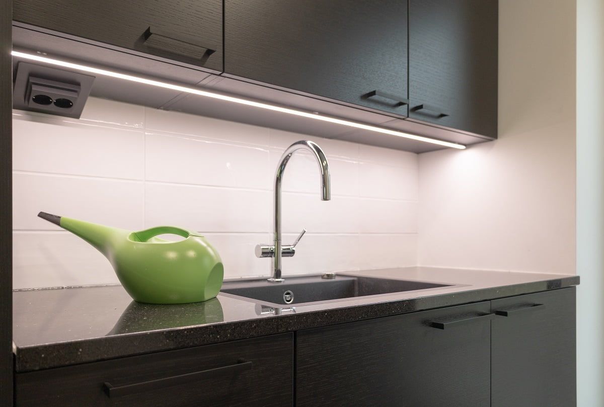 Kodinhoitohuoneen työtasolla tumman pinnan valaisee led-nauha mustassa alumiiniprofiilissa. ©LedStore